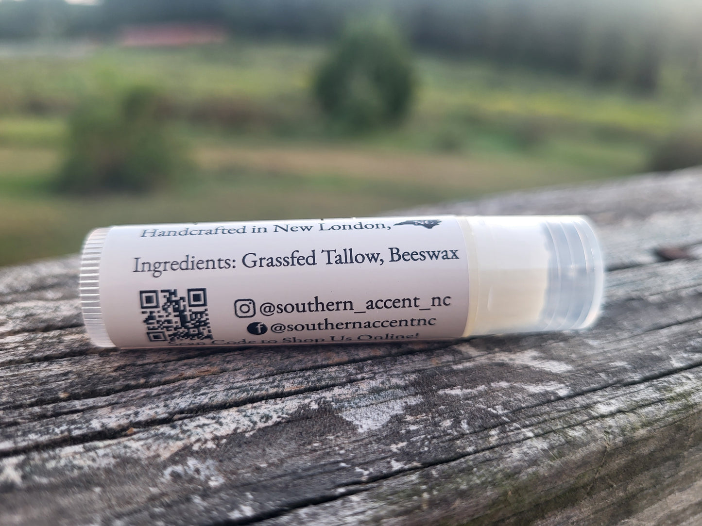 Lip balm tube with label on a wooden surface with a blurred natural background