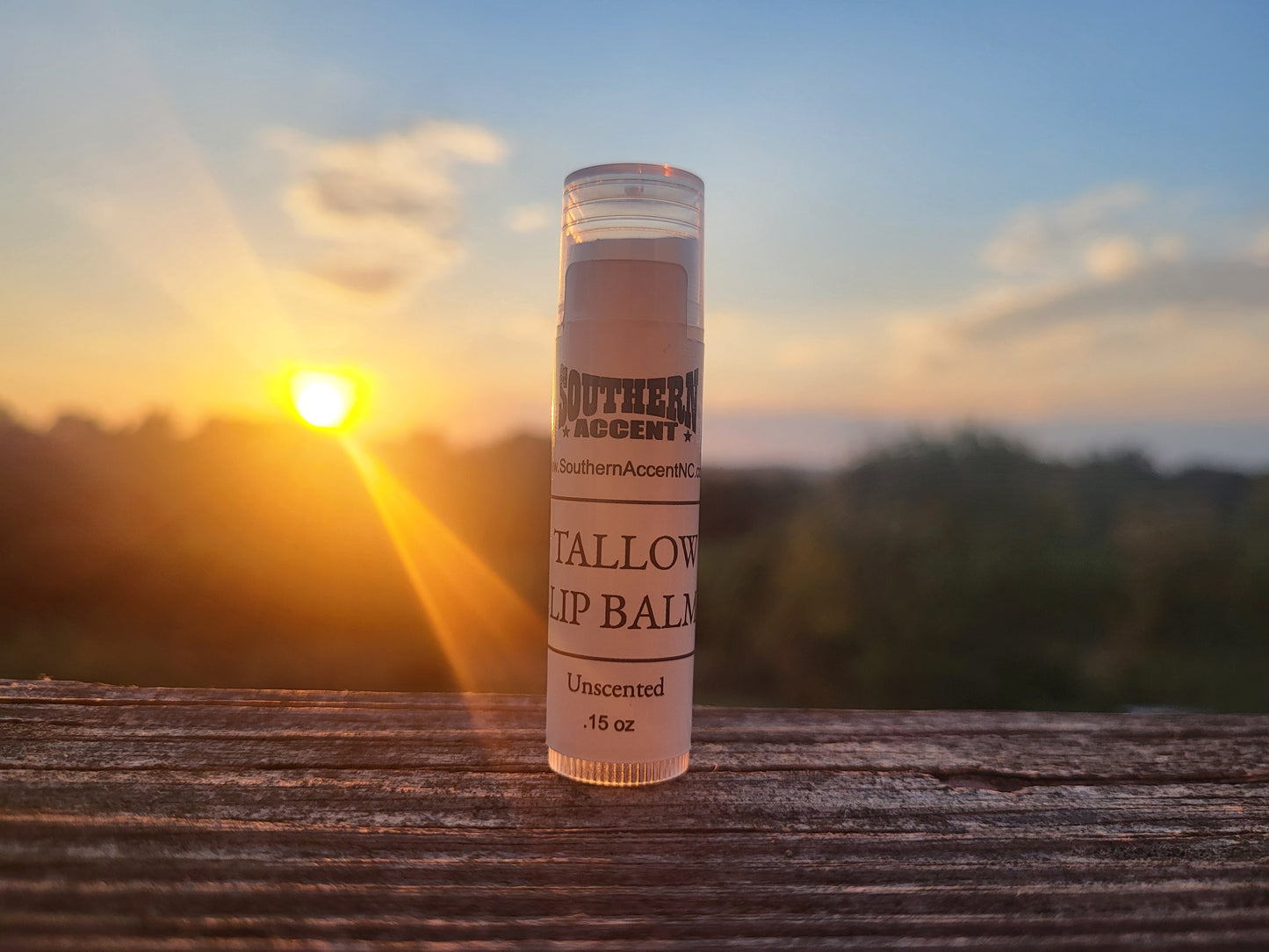 Lip balm stick with 'Southern Accent' branding against a sunset background