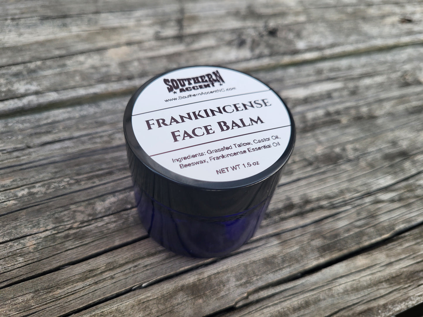 Blue jar of Southern Accent Frankincense face balm on an old, worn wooden surface