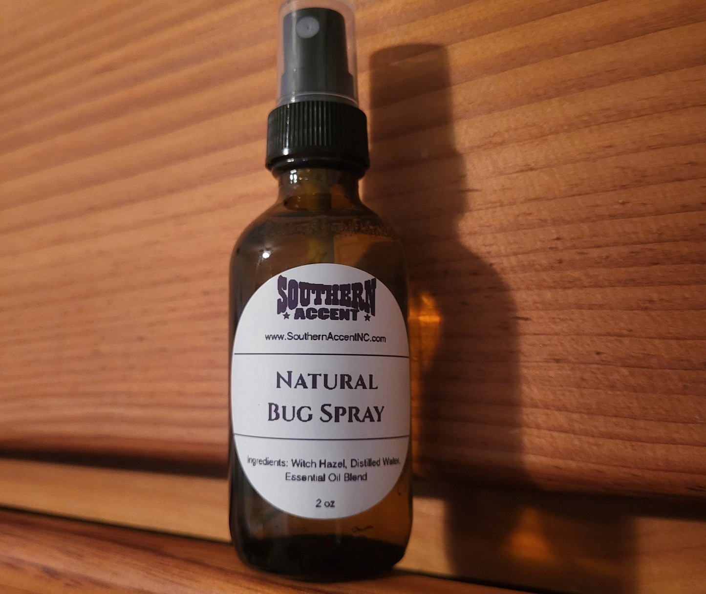 Amber glass bottle of natural bug spray on a wooden surface