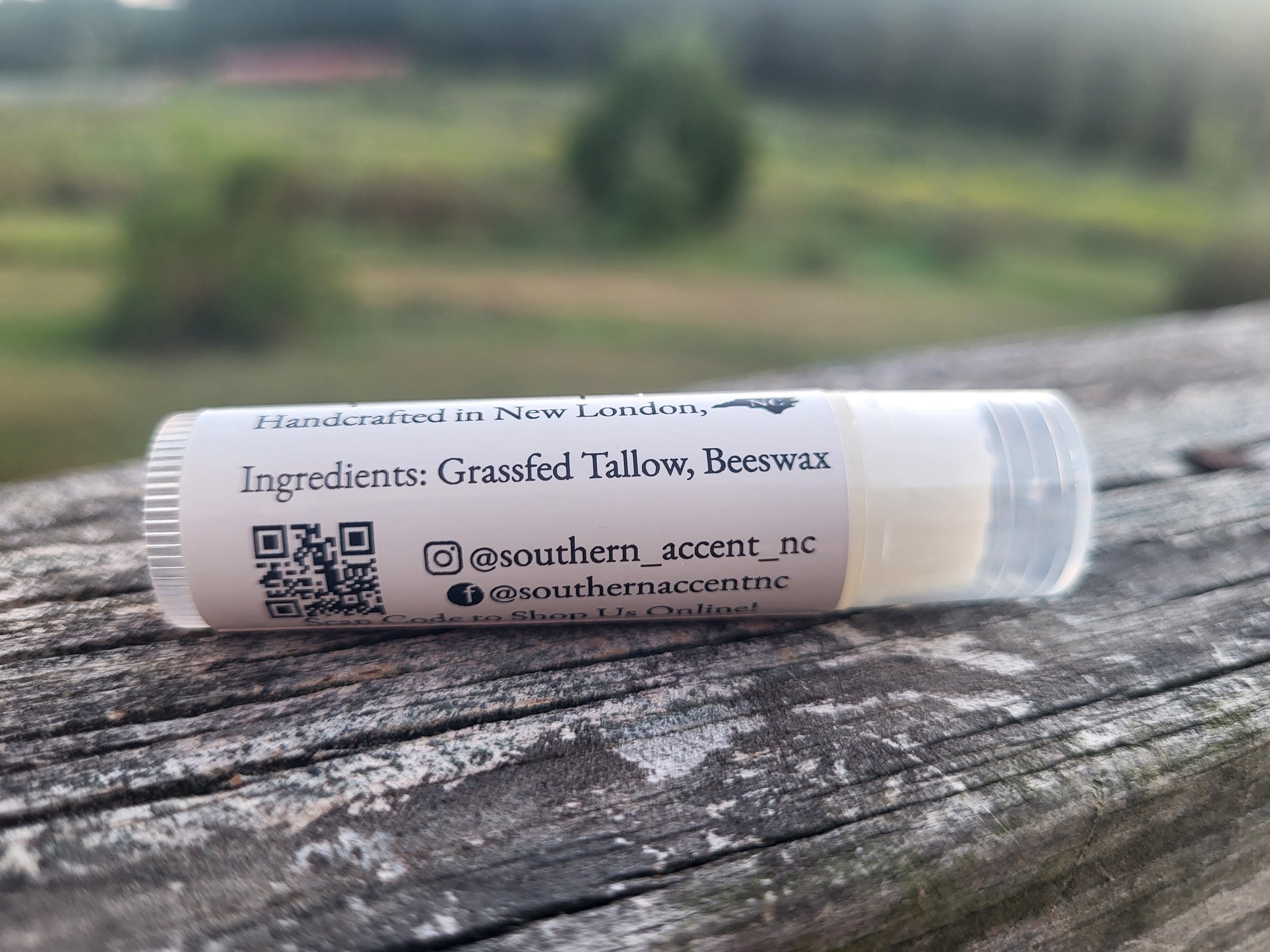Lip balm tube with label on a wooden surface with a blurred natural background