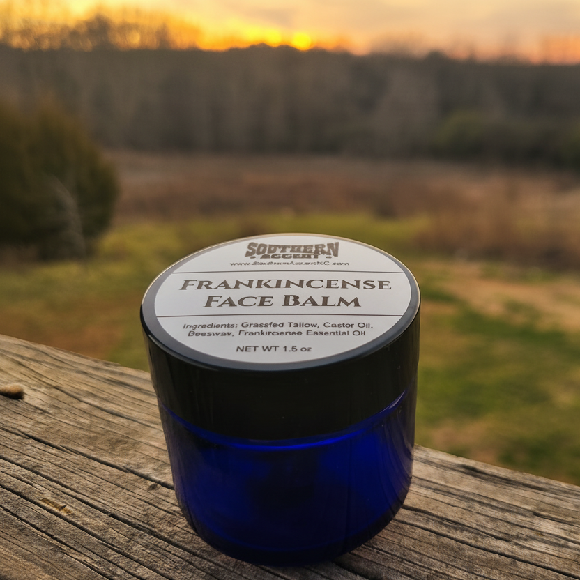 Blue jar of Southern Accent Frankincense Face Balm on a wooden surface with a blurred natural landscape in the background