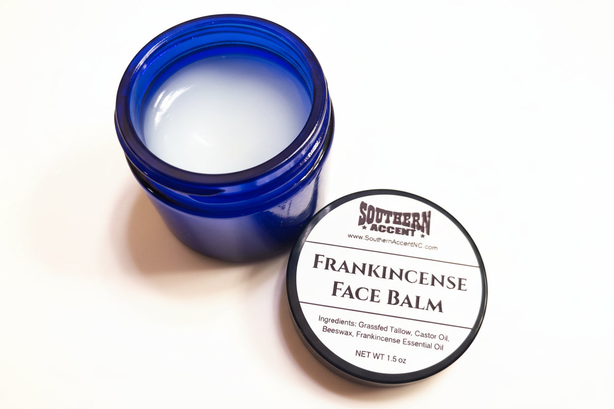 Opened blue jar of soothing Southern Accent Frankincense Face Balm with label showing on black lid on bright beige background